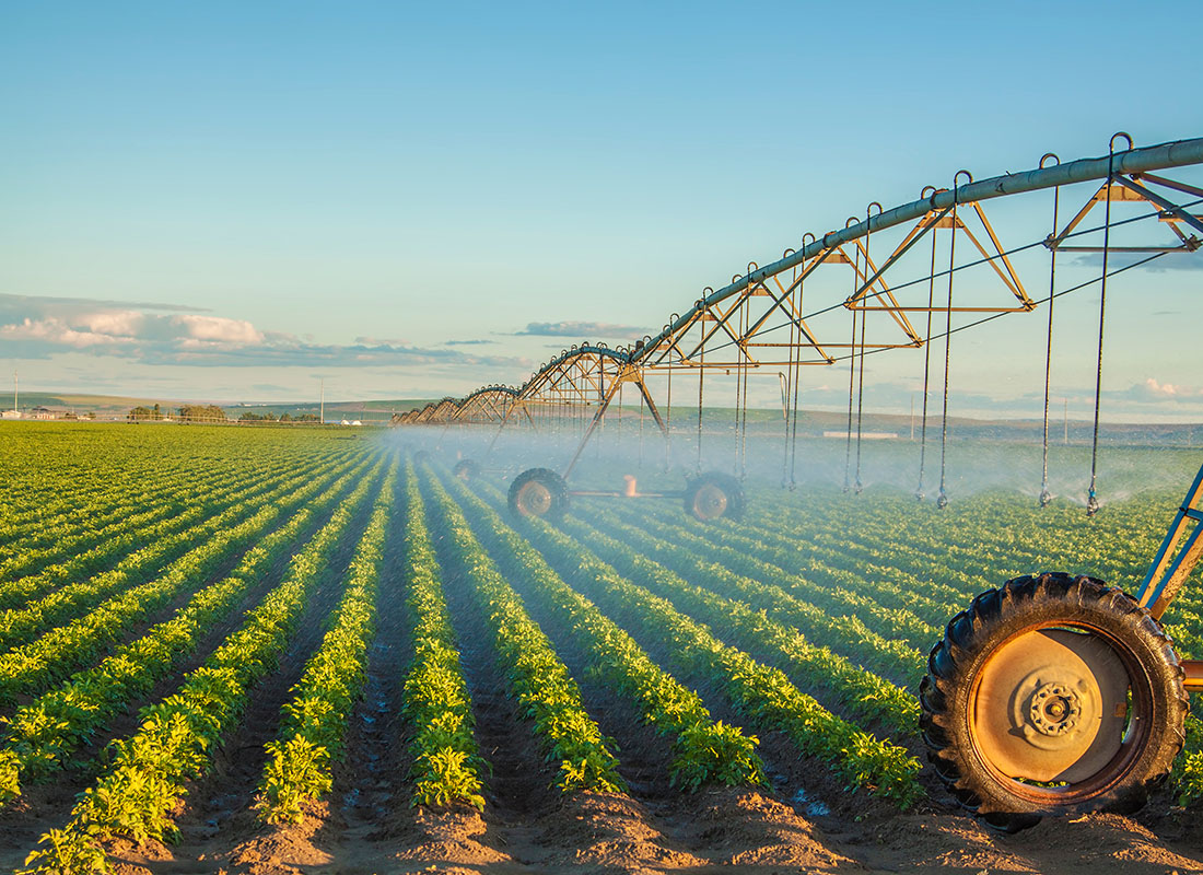 Insurance by Industry - Farming Equipment Spraying a Field of Young Potatoes Growing on a Commercial Farm in Idaho with a Clear Blue
