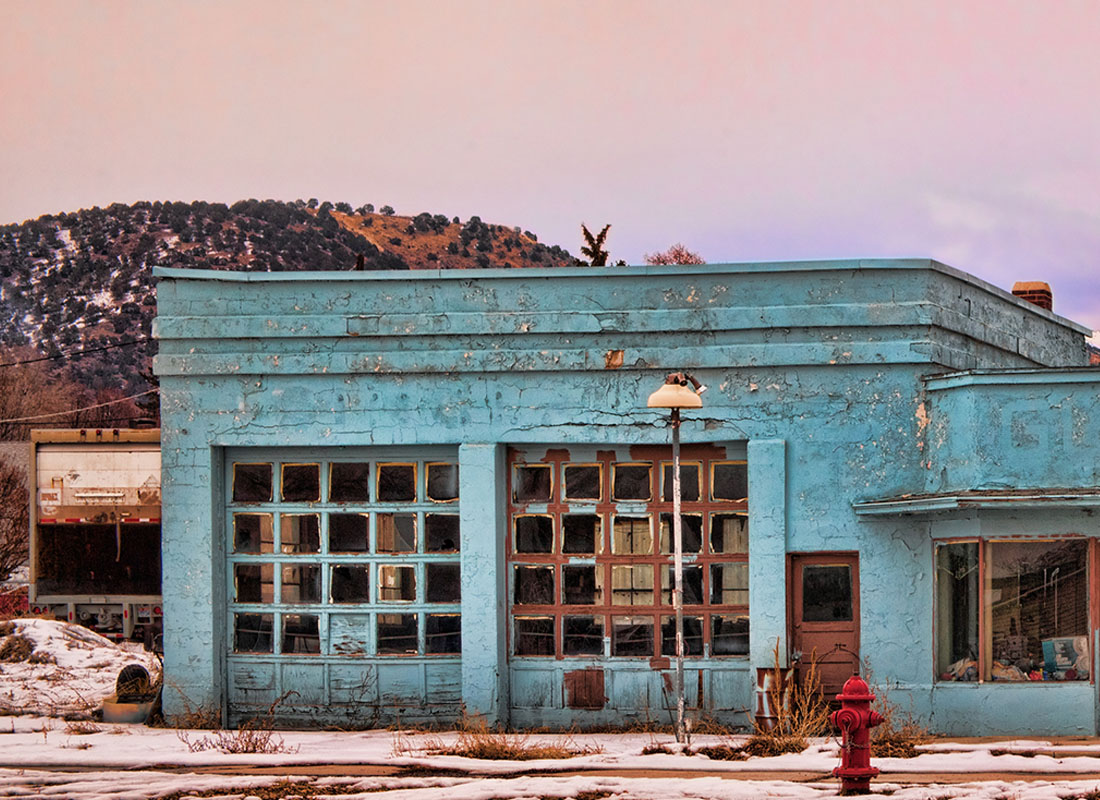 Service Center - Exterior View of an Old Abandoned Building in a Rural Town with a Mountain in the Background During the Winter